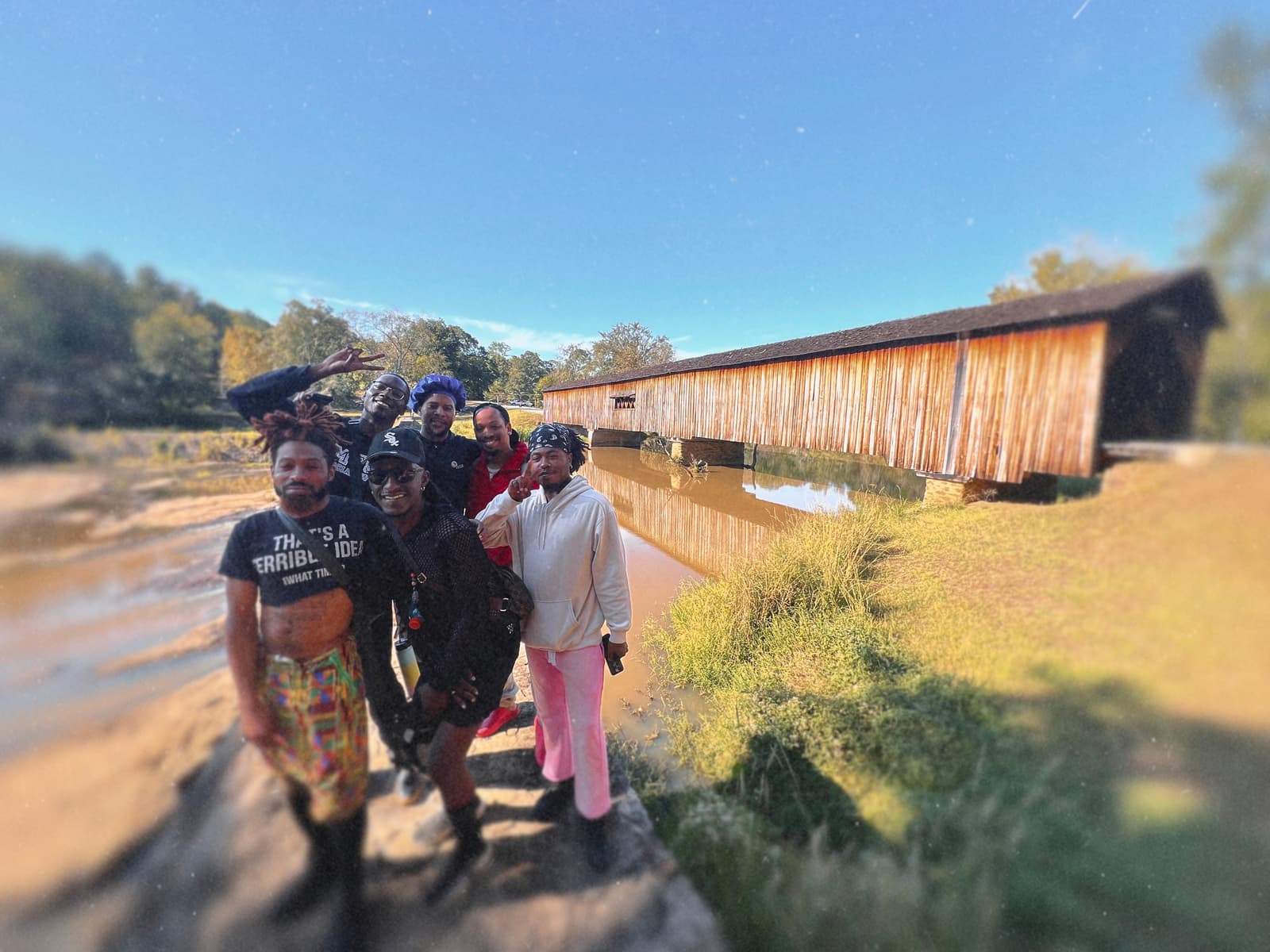Six Black hikers gather for a bright selfie beside the creek and Watson Mill’s covered bridge.