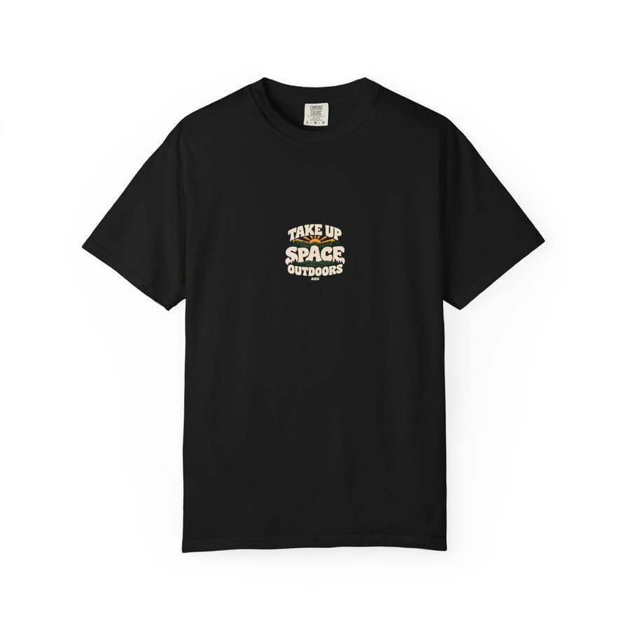 Front product mockup of a black ABH T-shirt with a small centered Take Up Space Outdoors forest-and-sun graphic and ABH signature.